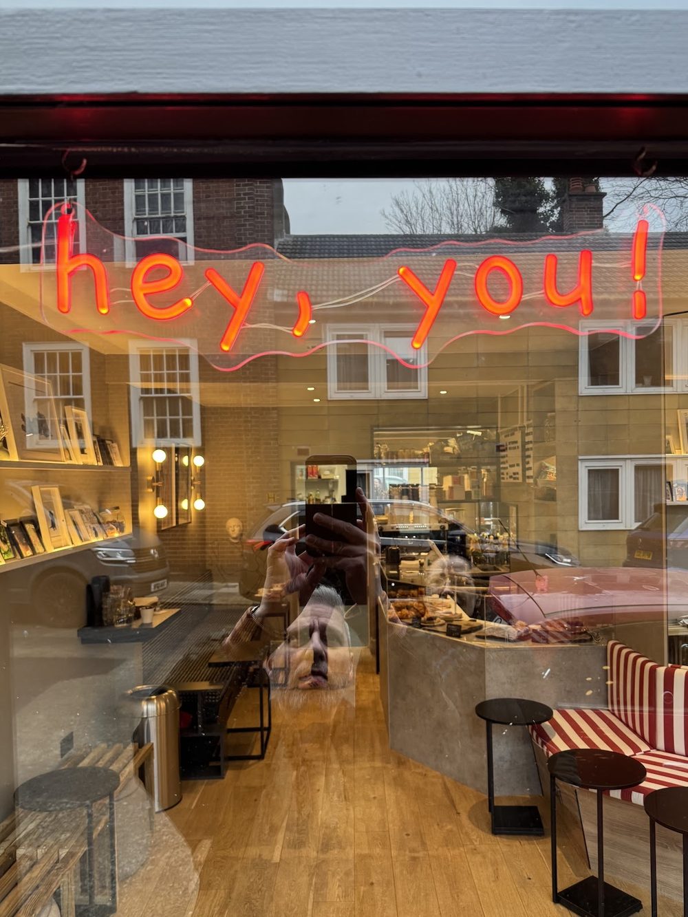 Caprini's shopfront on Arlington Way at dusk, red neon glowing in the window with the warm interior behind