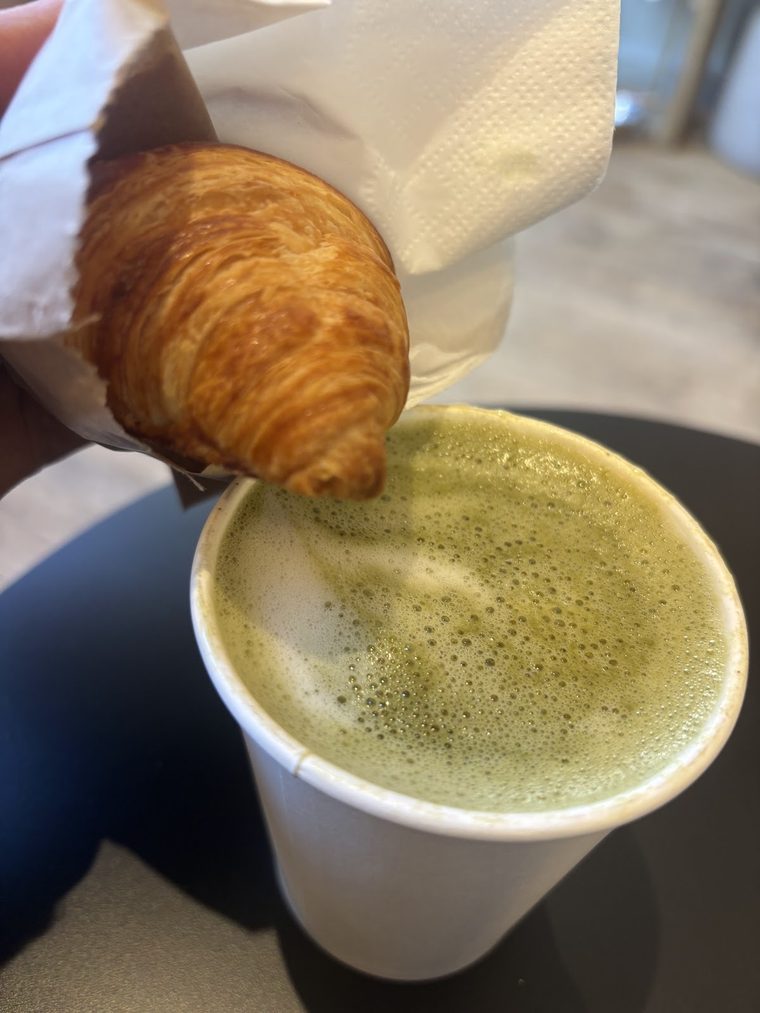 Takeaway matcha latte held with a croissant